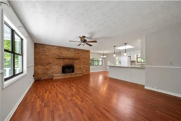 a view of a livingroom with wooden floor a fireplace and windows