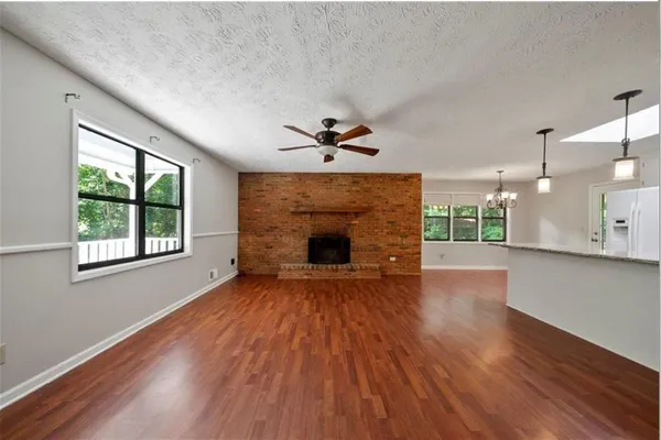 a view of an empty room with a fireplace and wooden floor