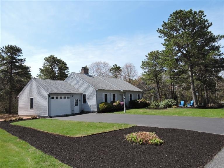130 Surf Drive Mashpee, MA 02649 - Photo 2 of 29 a front view of a house with a garden and trees