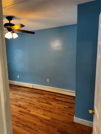an empty room with wooden floor chandelier fan and windows