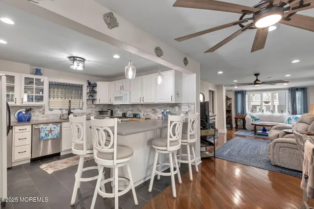 a large kitchen with cabinets chairs and wooden floor