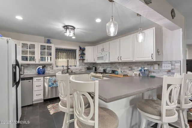 a kitchen with stainless steel appliances granite countertop a stove top oven a refrigerator a sink and chairs