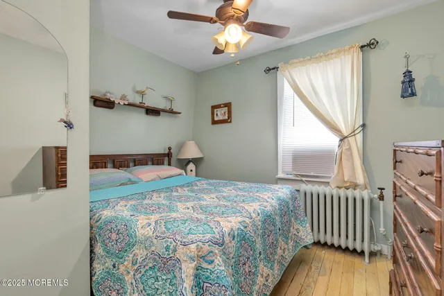 a bedroom with a bed next to a window with wooden floor