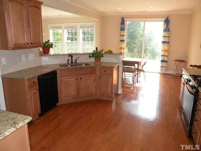 a open kitchen with granite countertop a stove a sink a dining table and chairs