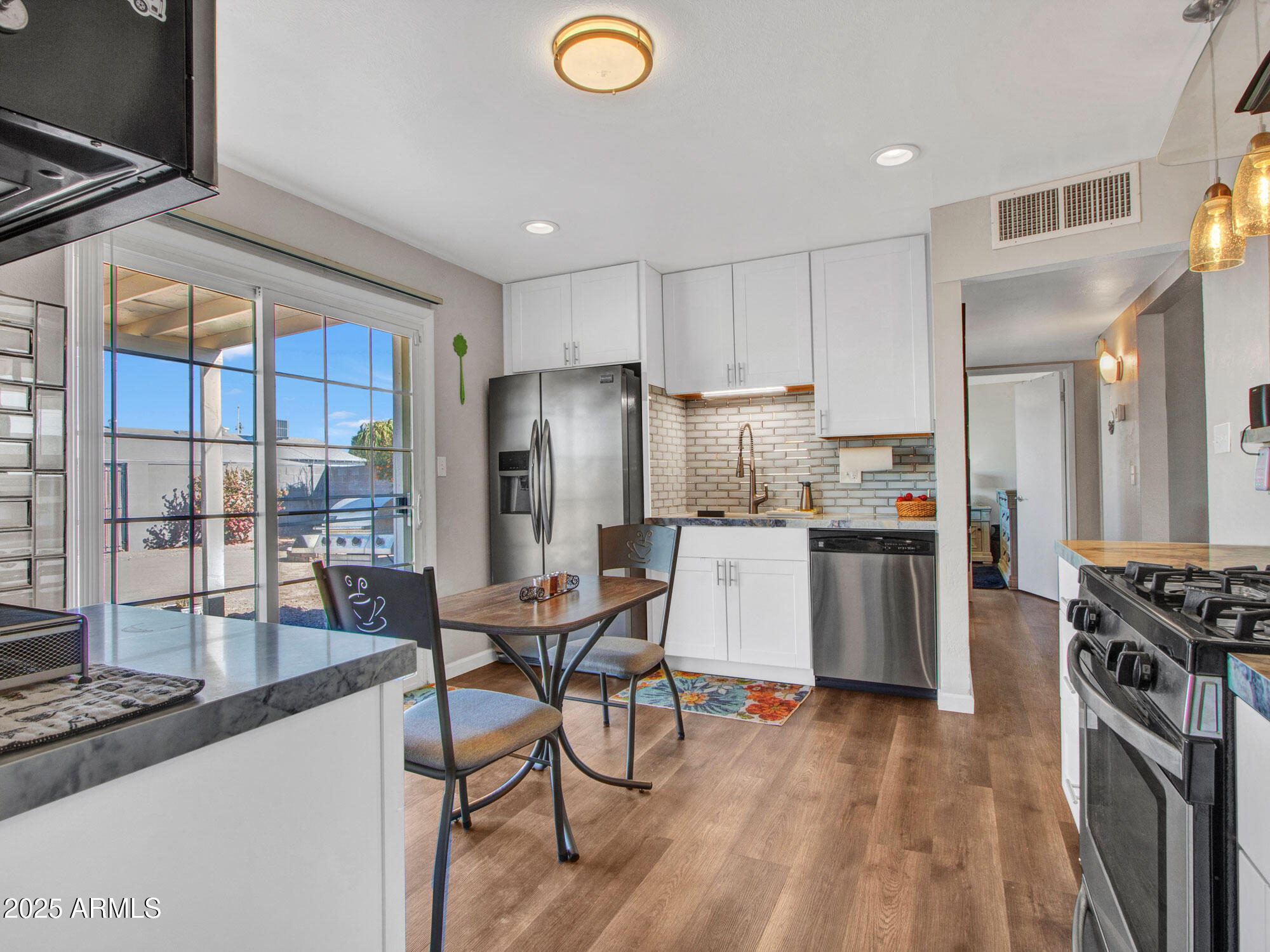 3328 West Charter Oak Road Phoenix, AZ 85029 - Photo 3 of 39 a kitchen with stainless steel appliances kitchen island granite countertop a refrigerator a stove a sink and white cabinets with wooden floor