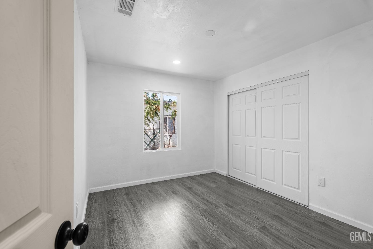 Undisclosed Address Bakersfield, CA 93307 - Photo 8 of 15 an empty room with wooden floor and window