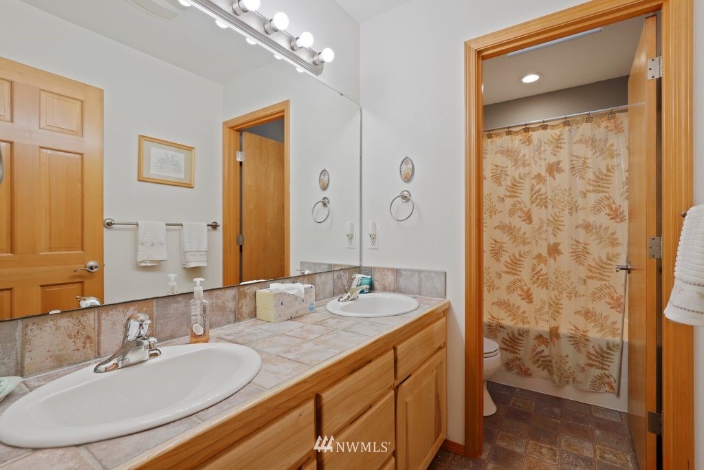 10606 Wagner Road Snohomish, WA 98290 - Photo 27 of 40 a bathroom with a granite countertop sink a mirror and a shower