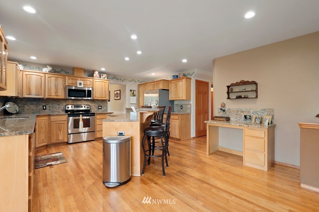 10606 Wagner Road Snohomish, WA 98290 - Photo 8 of 40 a kitchen with stainless steel appliances granite countertop a refrigerator oven a sink a stove and white cabinets with wooden floor