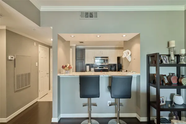 a living room with stainless steel appliances kitchen island granite countertop a table chairs and a refrigerator