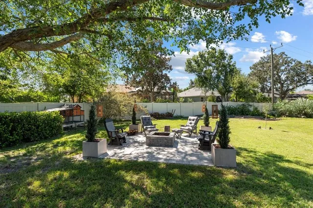 a view of a patio with table and chairs potted plants and a large tree