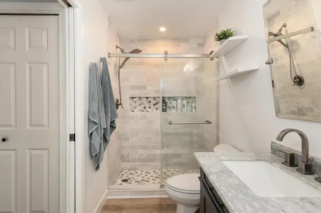 a bathroom with a granite countertop sink a mirror and shower