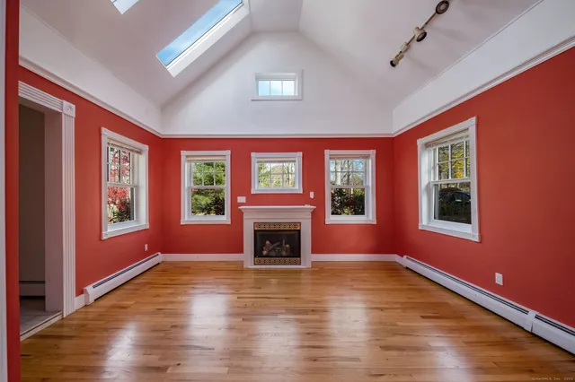 a view of an empty room with window wooden floor and fire place