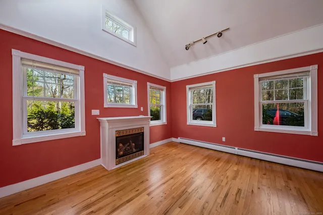 a view of an empty room with window fireplace and wooden floor