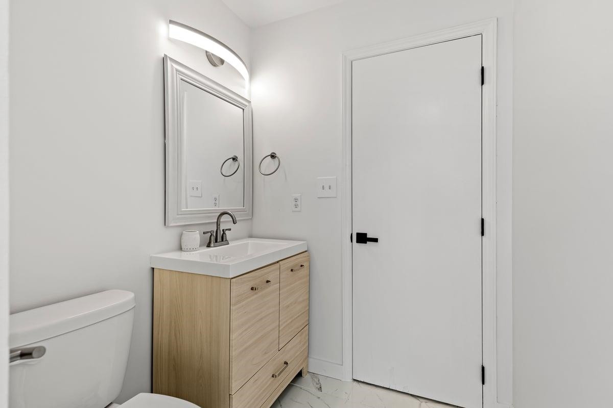 2718 Omah Street Durham, NC 27705 - Photo 14 of 20 a bathroom with a granite countertop sink a toilet and a mirror
