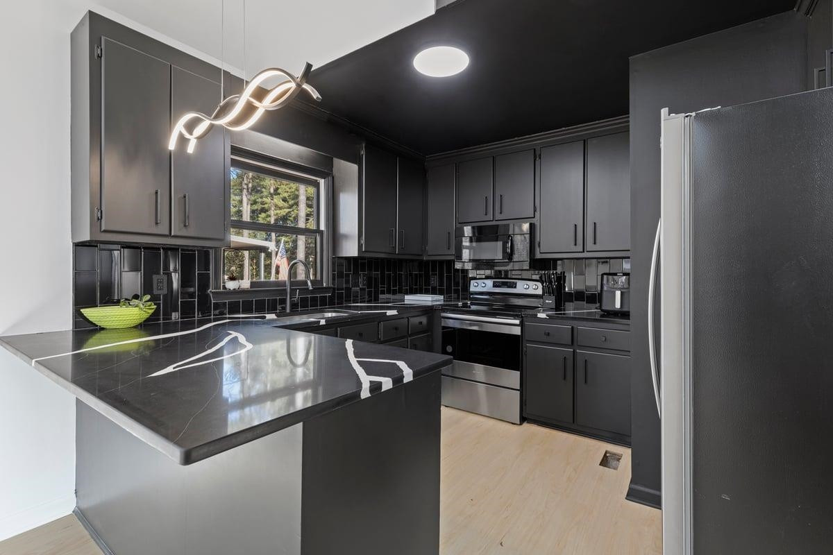 2718 Omah Street Durham, NC 27705 - Photo 10 of 20 a kitchen with a refrigerator a sink a stove a microwave and cabinets
