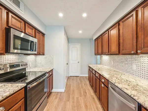 a kitchen with granite countertop wooden cabinets stainless steel appliances and a sink