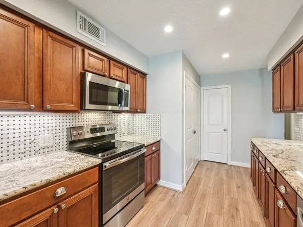a kitchen with granite countertop stainless steel appliances a sink stove top oven and cabinets