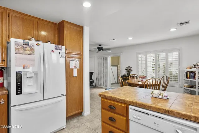 a kitchen with stainless steel appliances granite countertop a refrigerator a sink a stove a dining table and chairs