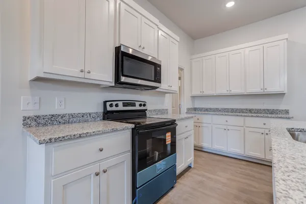 a kitchen with stainless steel appliances granite countertop white cabinets sink and stove top oven