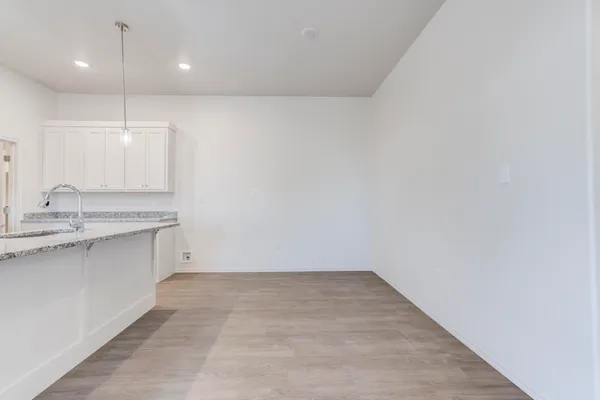 an empty room with a sink and dishwasher with wooden floor