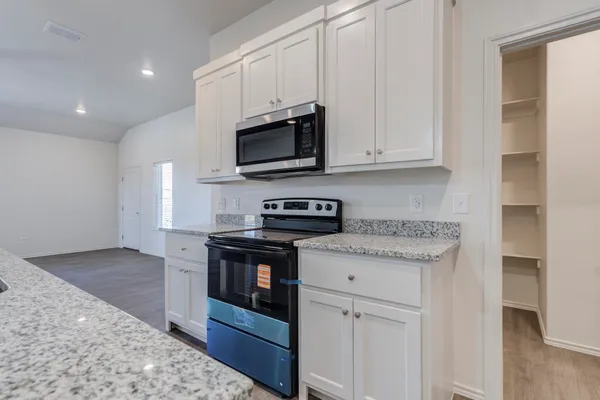 a kitchen with stainless steel appliances granite countertop a stove a sink and a microwave
