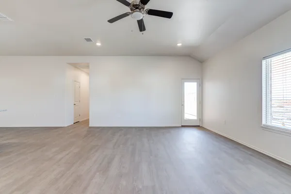 an empty room with wooden floor fan and windows
