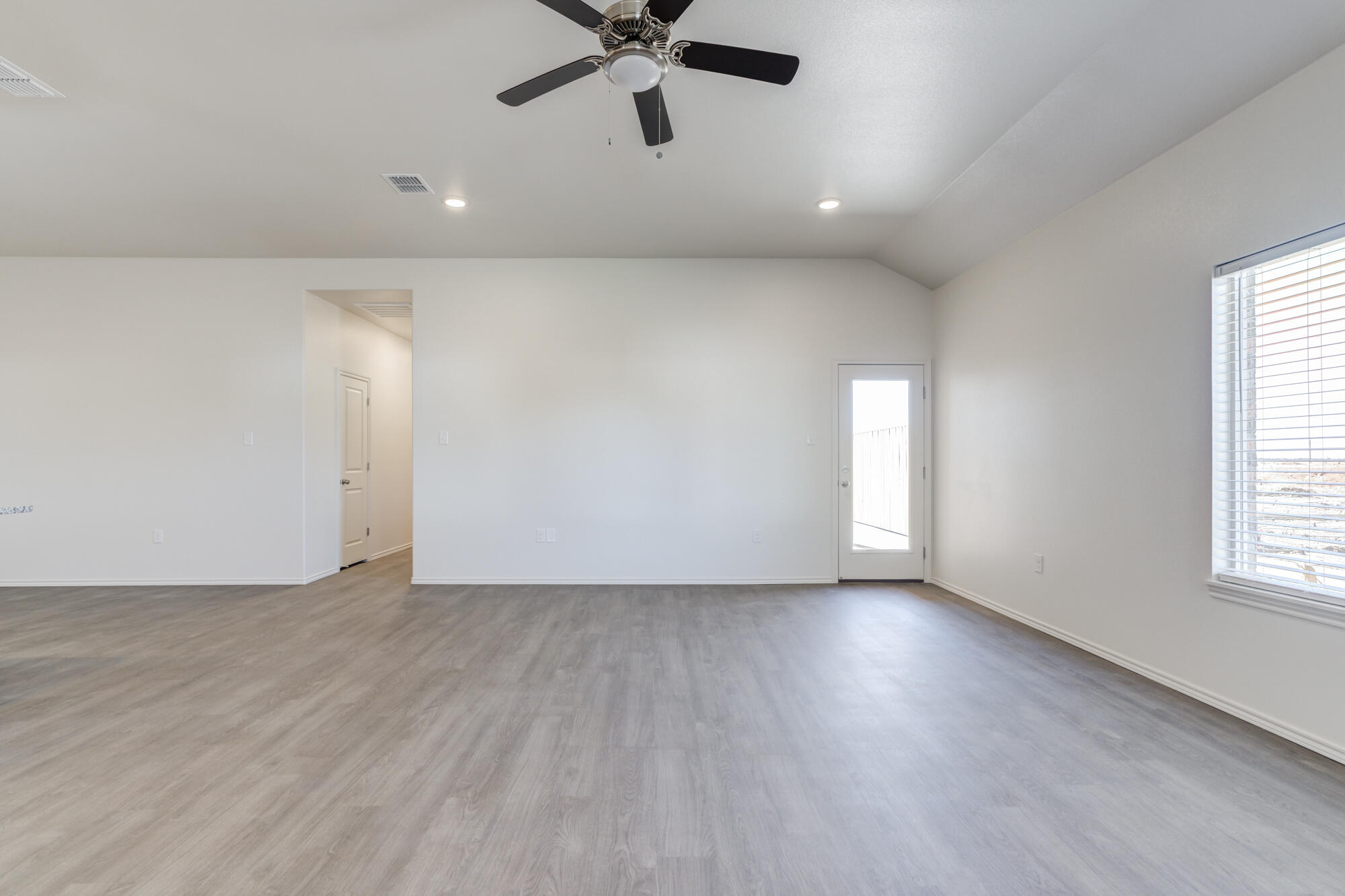 7011 40th Street Lubbock, TX 79407 - Photo 3 of 32 an empty room with wooden floor fan and windows