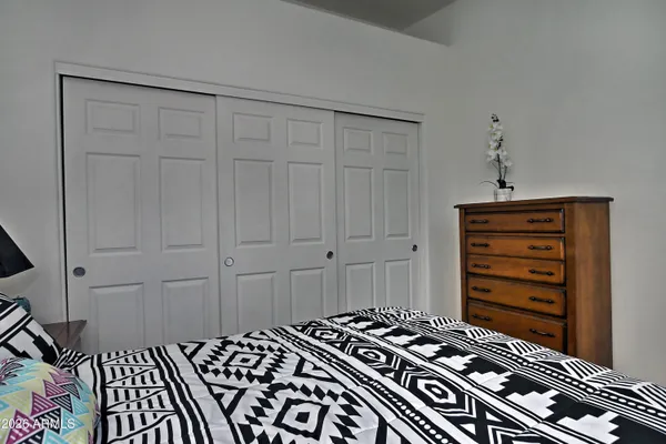a bedroom with a bed and a lamp on dresser