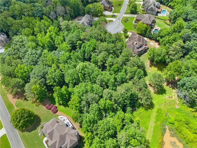 an aerial view of residential house with outdoor space and trees all around