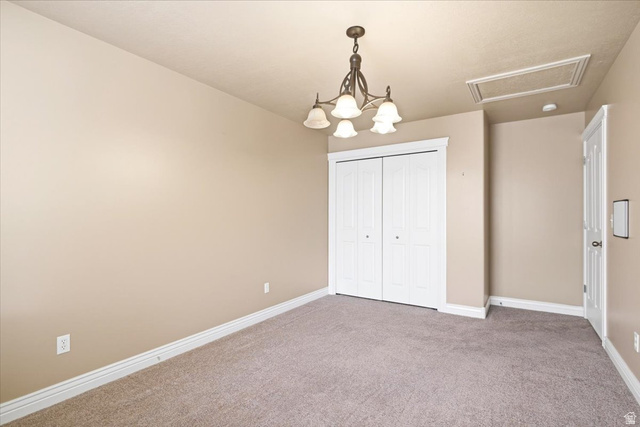 1089 West 2325th Street North Layton, UT 84041 - Photo 23 of 40 Carpeted room featuring a ceiling-mounted chandelier, white bi-fold closet doors, white baseboards, and a white interior door