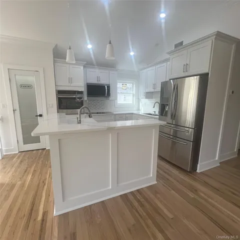 a kitchen with kitchen island white cabinets and stainless steel appliances