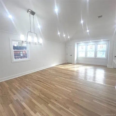 an empty room with wooden floor and outdoor view