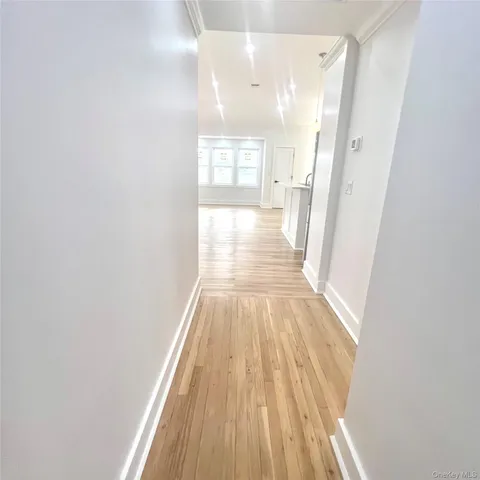 a view of a hallway with wooden floor and a bathroom