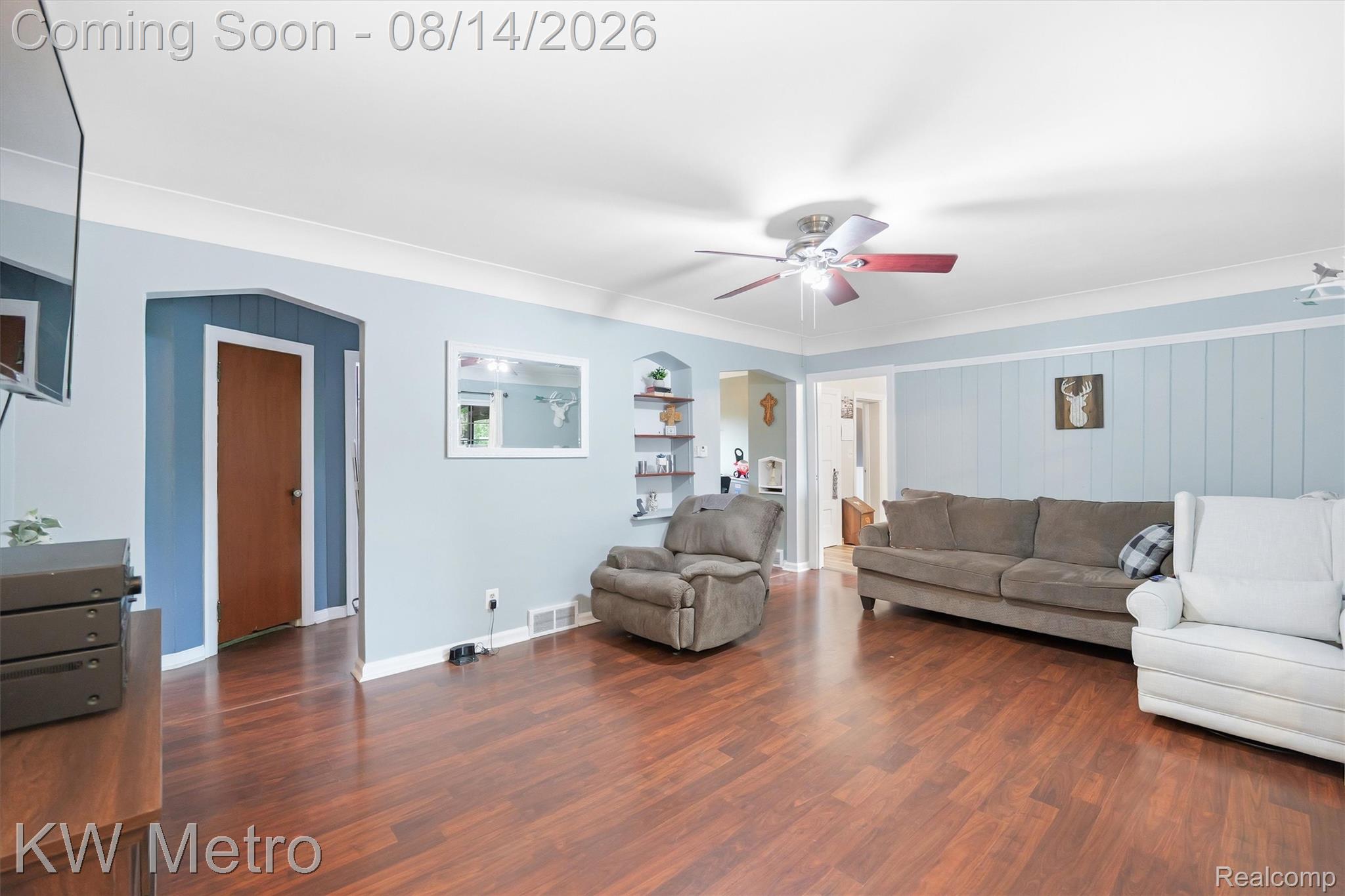 201 South Maple Leaf Road Lapeer, MI 48446 - Photo 16 of 70 Wood-finish flooring, light blue paneled accent wall, crown molding, and a ceiling fan with integrated lighting