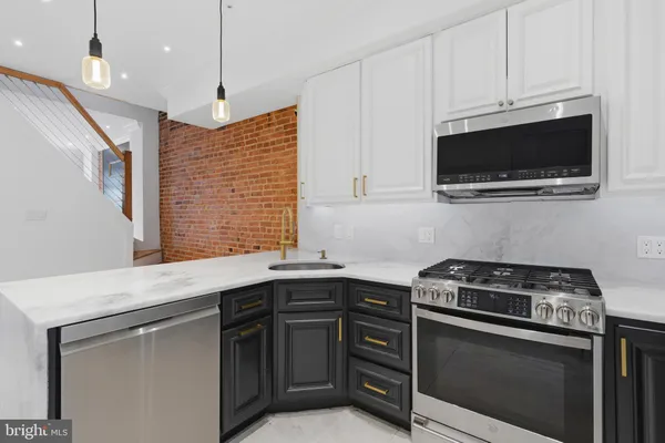 a kitchen with stainless steel appliances granite countertop a sink a stove a microwave and wooden cabinets