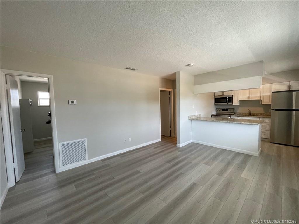 661 Hernando Street, Unit 9 Fort Pierce, FL 34949 - Photo 3 of 10 a view of kitchen with wooden floor electronic appliances and window