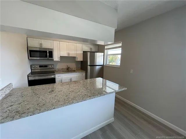 a kitchen with stainless steel appliances granite countertop a sink a stove and a refrigerator