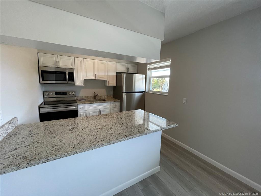 661 Hernando Street, Unit 9 Fort Pierce, FL 34949 - Photo 4 of 10 a kitchen with stainless steel appliances granite countertop a sink a stove and a refrigerator