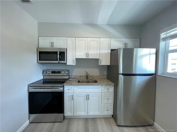 a kitchen with a refrigerator sink and stove top oven
