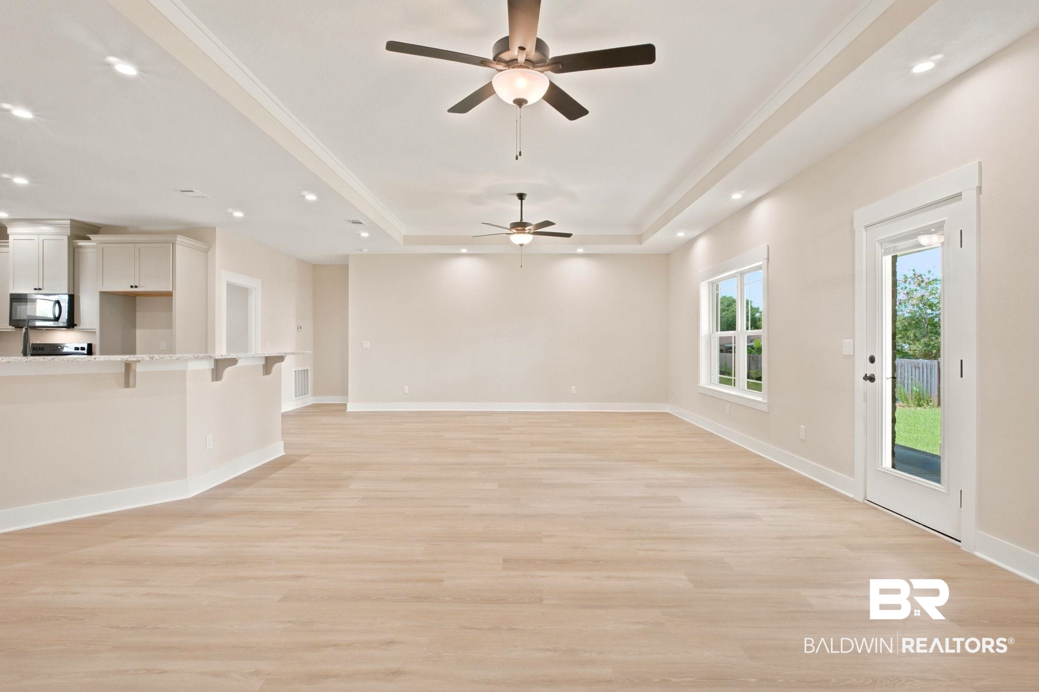 32656 Arbor Ridge Circle Lillian, AL 36549 - Photo 4 of 56 Spacious living area featuring light wood-finish flooring, a tray ceiling with recessed lighting and ceiling fans, and a kitchen pass-through with a light-colored countertop