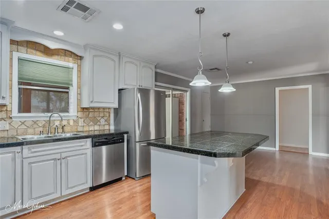 a kitchen with stainless steel appliances granite countertop a sink refrigerator and cabinets