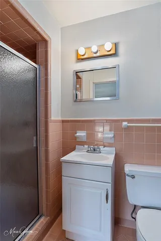 a bathroom with a sink a toilet a mirror and shower