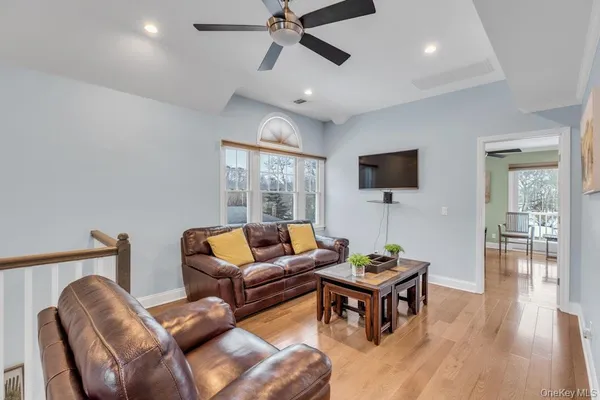 a living room with furniture a ceiling fan and a flat screen tv