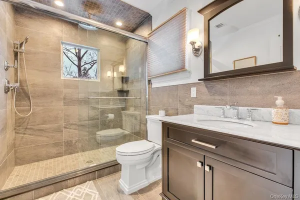 a bathroom with a granite countertop sink mirror vanity and toilet