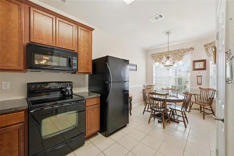 a kitchen with stainless steel appliances granite countertop a stove top oven a refrigerator a dining table and chairs with wooden floor