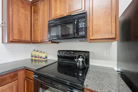 a kitchen with granite countertop a stove top oven microwave and cabinets