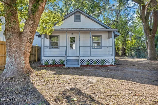 a view of a grey house with a yard and large tree