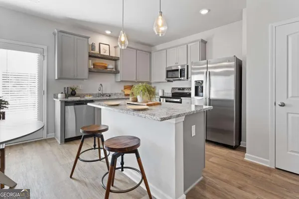 a kitchen with stainless steel appliances granite countertop a sink a stove a refrigerator cabinets and wooden floor
