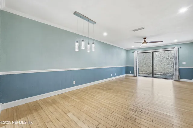 an empty room with wooden floor fan and windows