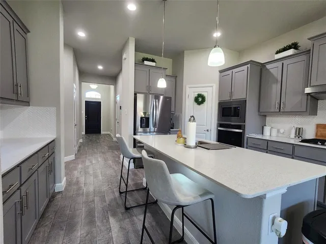a large kitchen with sink a refrigerator and chairs